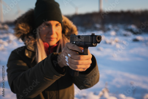 A girl takes aim from a pistol with a muzzle brake outdoors in winter. photo