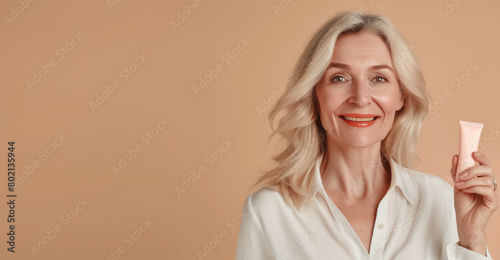 Mature woman smiling, holding a skincare product Mature woman smiling, holding a skincare product