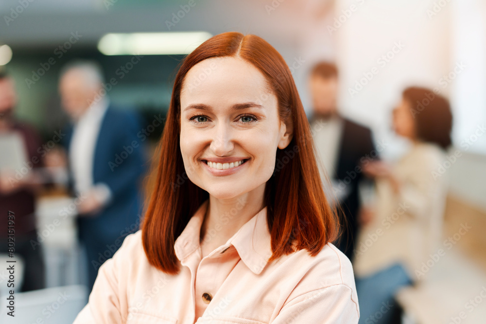 Portrait of attractive young ginger businesswoman wearing casual clothes looking at camera