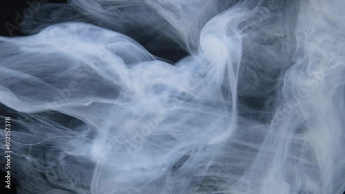 Wisps of smoke intertwine gracefully against a dark backdrop. (ID: 802157378)