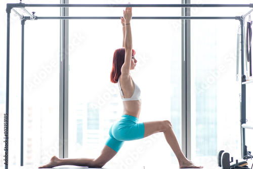 Beautiful woman performing pilates over white background with reverse light via daylight photo