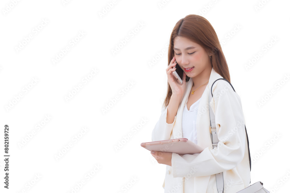 Young Asian business woman in white suit smiles and holds talk smartphone in her hands while holding tablet to search for information with business buildings while isolated white background. Young Asian business woman in white suit smiles and holds talk smartphone in her hands while holding tablet to search for information with business buildings while isolated white background.