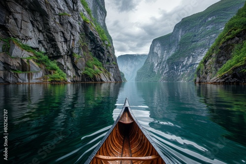 A boat peacefully glides through the calm waters of a fjord surrounded by towering cliffs © Ilia Nesolenyi