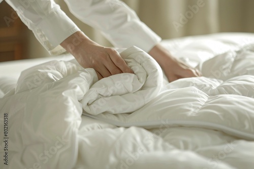 Hands of a housekeeper tucking in a fresh duvet over a hotel bed. ensuring a luxurious stay for guests. photo