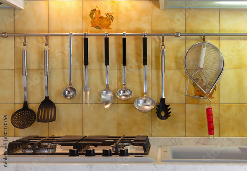 Stove of a modern kitchen with utensils hanging from a metal bar