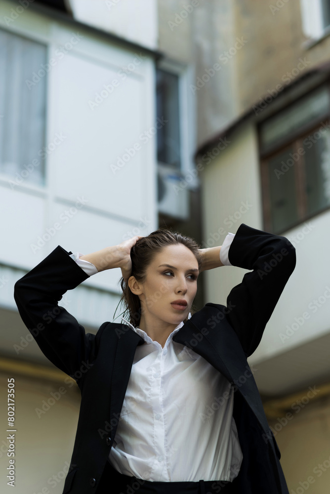 Attractive caucasian young woman in suit posing while walking outdoors on spring day. Luxurious, sexy and elegant lady. Beauty, Fashion, Style, Lifestyle.