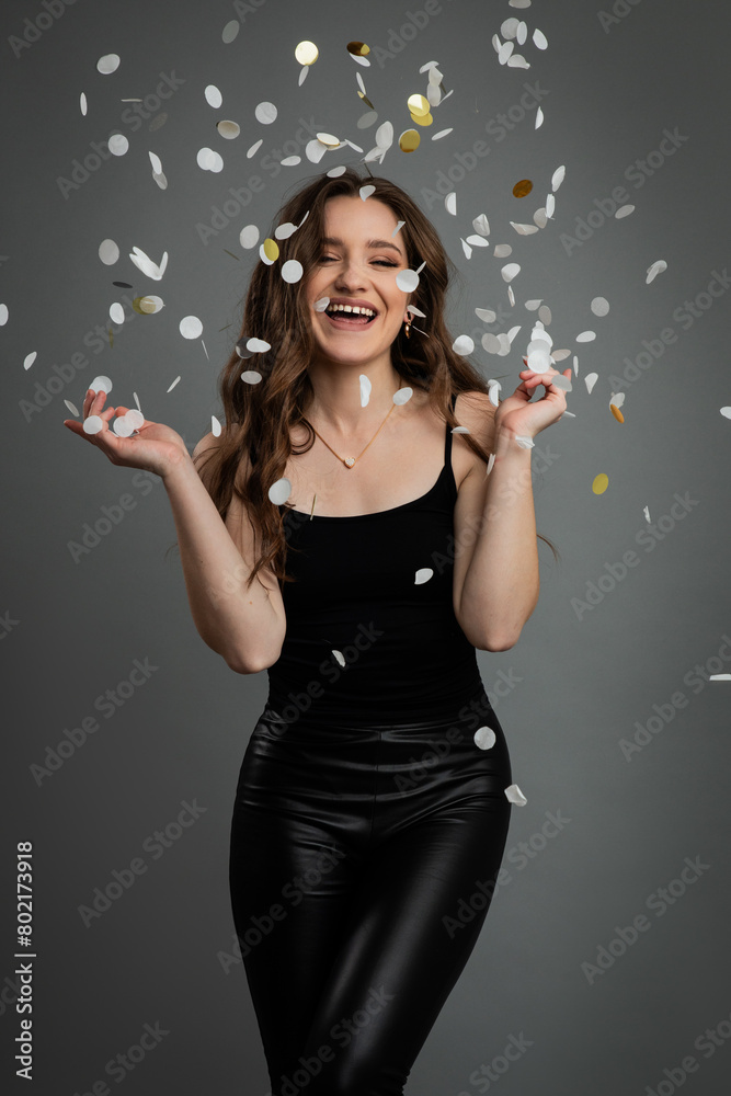Studio portrait of young beautiful happy woman in black outfit against gray background. Studio portrait of young beautiful happy woman in black outfit against gray background.