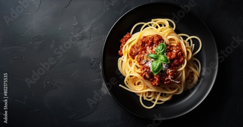 Spaghetti with tomato sauce and basil on a black plate photo