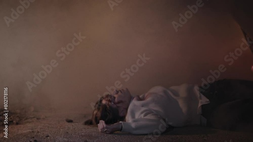 A young woman laying on the ground after a car crash