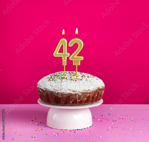 Birthday cake with number 42 candle on pink background