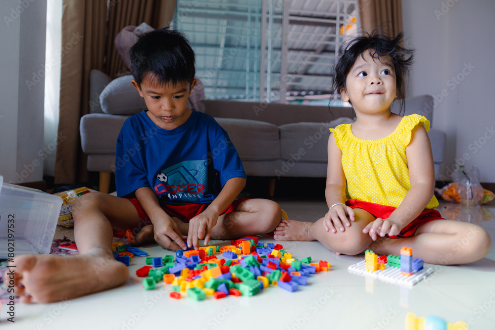 Happy adorable kindergarten boy and girl enjoying play toy block building in cozy house Happy adorable kindergarten boy and girl enjoying play toy block building in cozy house