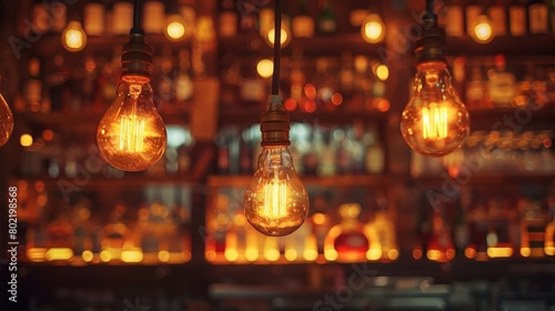 Electrified light bulbs dangle with a soft glow in a lounge, a shimmering array of backlit spirits bottles creating a cozy ambiance.