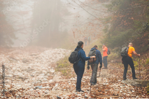 A diverse group of hikers making their way up a challenging rocky trail, surrounded by stunning mountain scenery photo