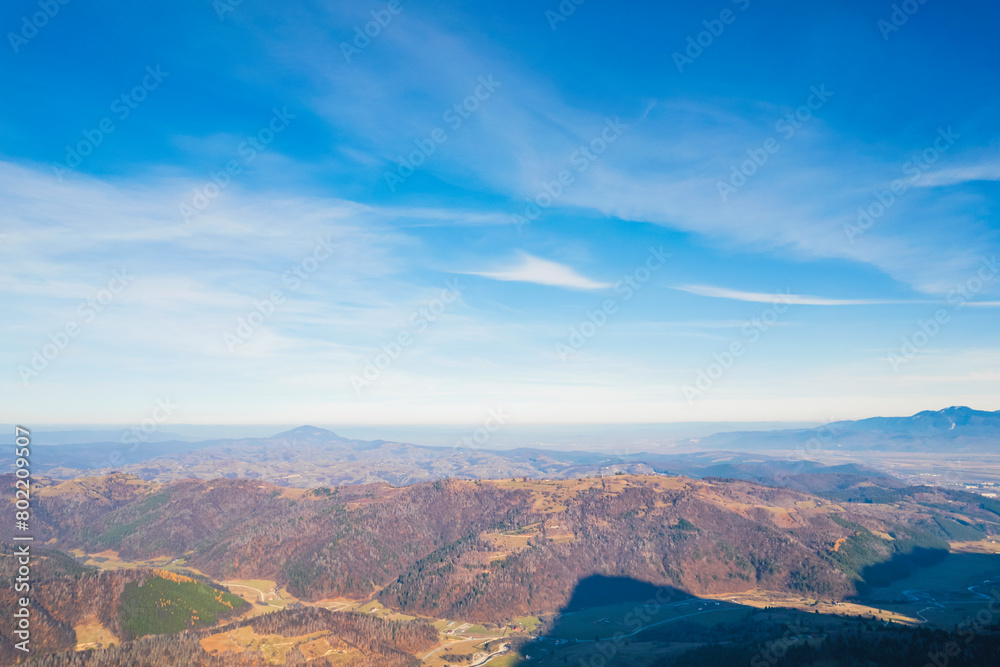 A stunning vista unfolds below, with towering mountains stretching in a grand symphony of nature viewed from a plane soaring high