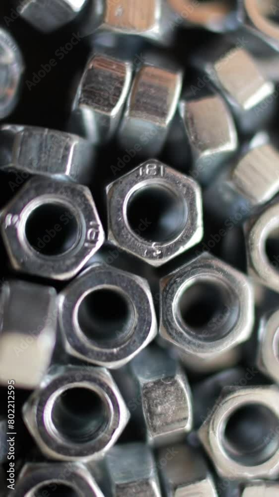 Many stainless hex nuts rotating close-up. Metal industry concept. Vertical video. Many stainless hex nuts rotating close-up. Metal industry concept. Vertical video.