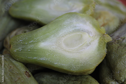 Steamed fruit of small Chayote or Sicyos edule, on wooden plate, isolated on white background photo