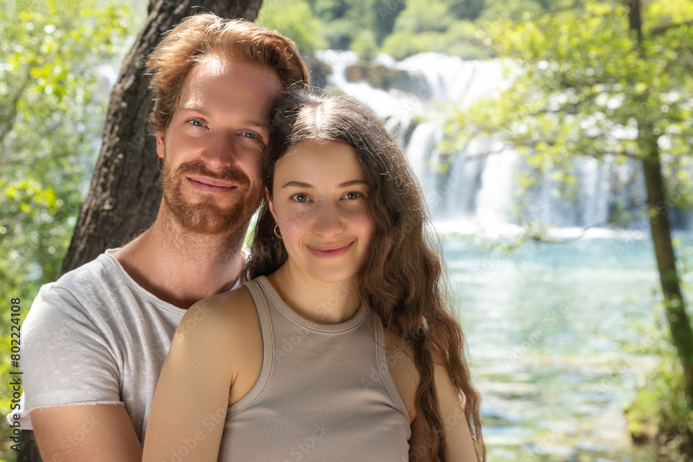 Fototapeta premium The couple of young people in nature park in Croatia. Waterfall on the background.