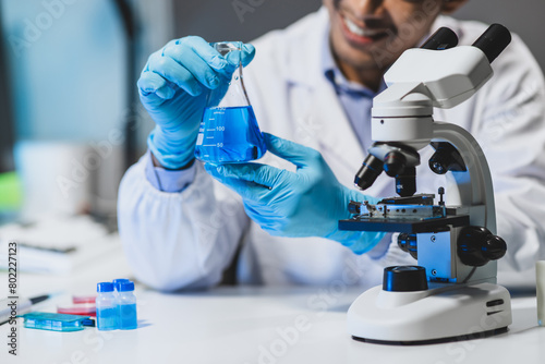 Scientist experimenting with chemicals in lab. Lab technician doing research on new chemicals in laboratory, adding solution in conical flask.