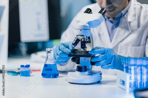 Doctor or scientist in laboratory looking at microscope.