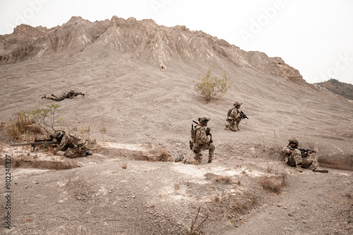 Soldiers in camouflage uniforms aiming with their rifles.ready to fire during military operation in the desert , soldiers training  in a military operation