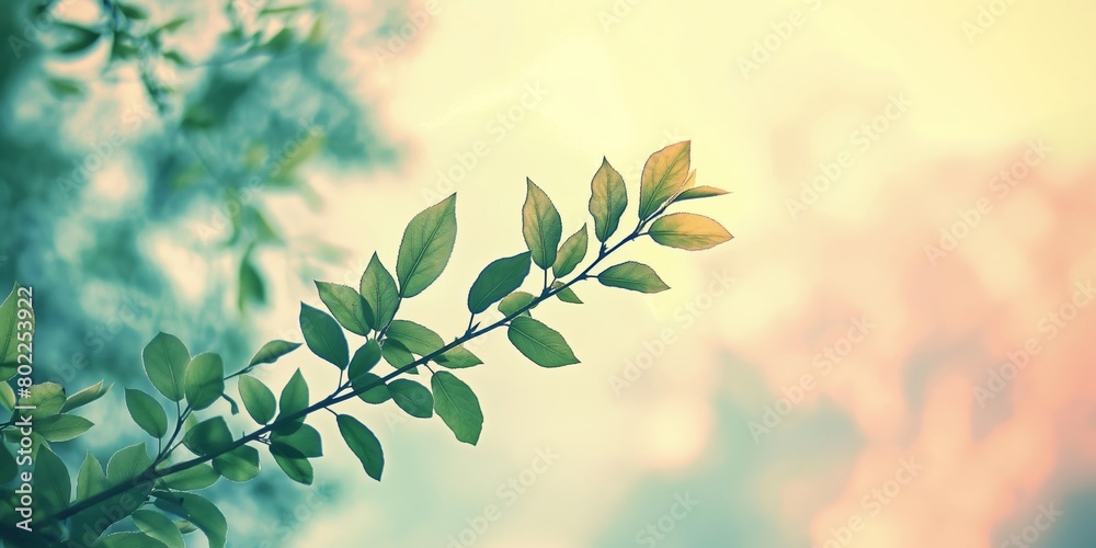 Obraz premium A fresh branch with green leaves stands out with sunlight filtering through, against a soft pastel bokeh background