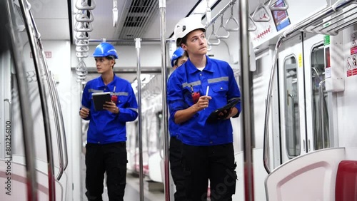 team of male engineers wearing a uniform carrying radios inspect the safety of electric trains and the cleanliness of electric trains in the electric train maintenance station. photo