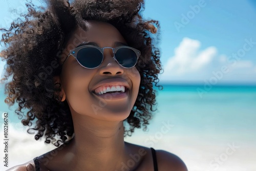 A young black woman with curly hair wearing sunglasses smiling and enjoying summer vacation .