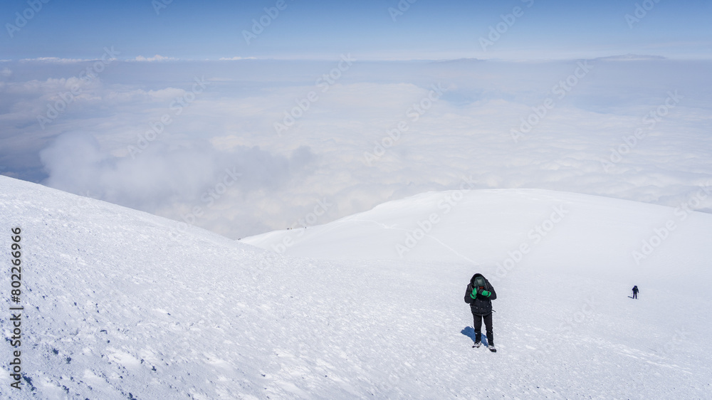 Mountaineers walking towards the snowy mountain summit above the clouds, Mount Ararat in Turkey