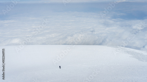 Solo mountaineer walking big glacier field above the clouds, Mount Ararat in Turkey