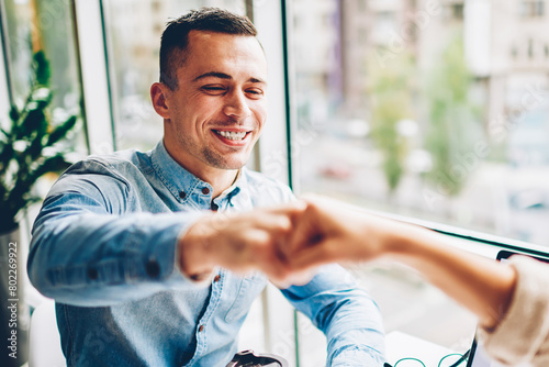 Cheerful male employee bumping fist making gesture of agreement satisfied with collaboration process,cropped image happy businessman knuckles with colleague making deal during planning startup photo