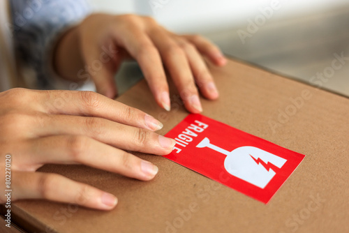 Woman Hand Sticking Fragile Mark Sticker to Parcel.