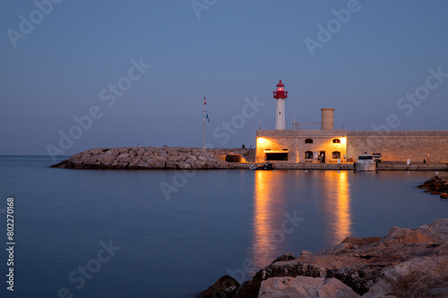 View of the lighthouse, sea and evening city of Menton, France
