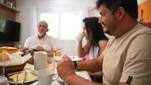  Família sentada a mesa pra tomar café da manhã, reunião de família, família feliz comendo. Mesa de café da manha com frutas e pão photo