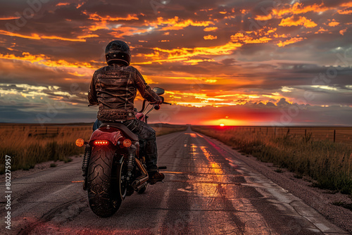 Motorcyclist riding into sunset on open highway