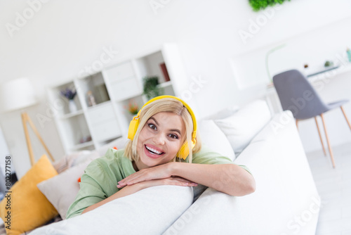 Photo of glad funny amazing girl sitting on comfy white sofa listening stereo audio melody good mood indoors © deagreez
