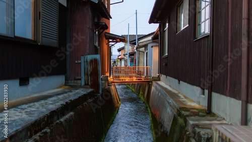 Footbridge over canal between traditional Japanese houses at dusk in Takeda, Japan