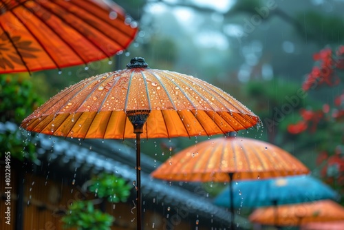 Close-up focus on raindrops on vibrant orange umbrellas  with rain shower creating a serene mood