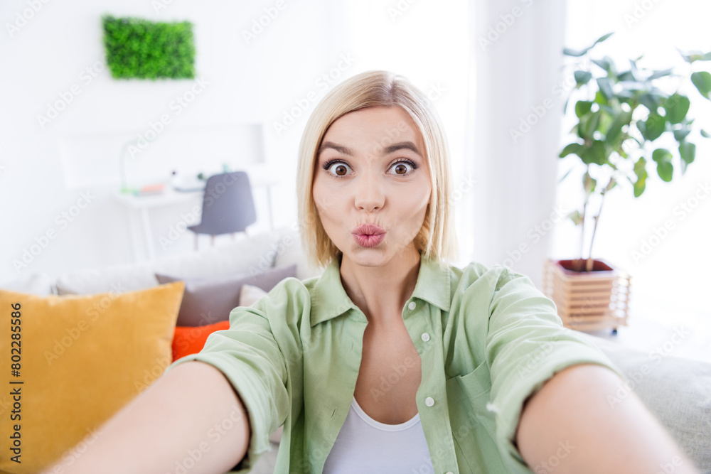 Selfie photo of pouted lips young lady wearing casual khaki shirt sending kisses to her boyfriend when she is in hotel room apartment Selfie photo of pouted lips young lady wearing casual khaki shirt sending kisses to her boyfriend when she is in hotel room apartment