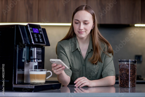 Female controlling coffee machine with phone at home. Smart home concept