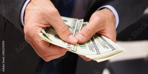 Man in suit and tie hold in arm pack of hundred dollar bills closeup. Stock market exchange earn pile rich present gift employer prepayment service gratitude concept photo