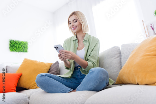 Full body length photo of relaxing lady in khaki shirt using smartphone order pizza when sitting comfortable sofa at modern design home © deagreez