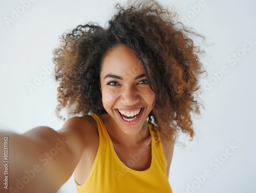 Cheerful young woman taking a selfie with a beaming smile and vivacious energy.