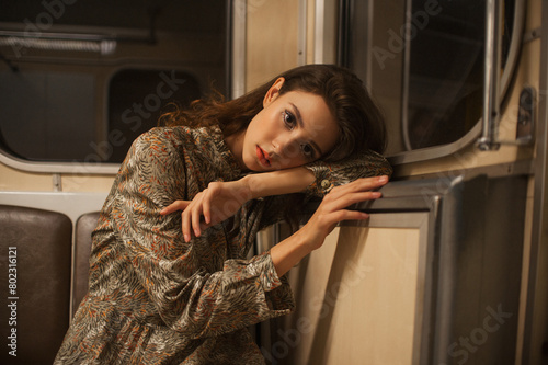 a young gentle girl in a subway car poses for a fashion photographer