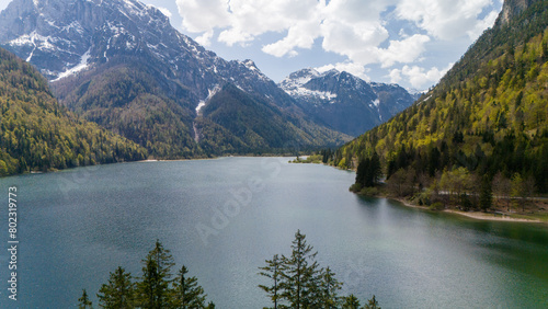 Photography Aerial photo of a beautiful tranquil alpine lake beneath the mountains on a sunny day