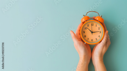 Female hand holding a alarm clock with blue background.