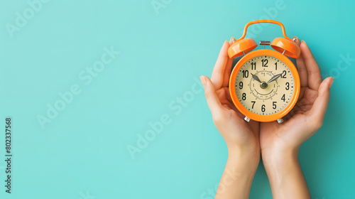 Female hand holding a alarm clock with blue background. photo