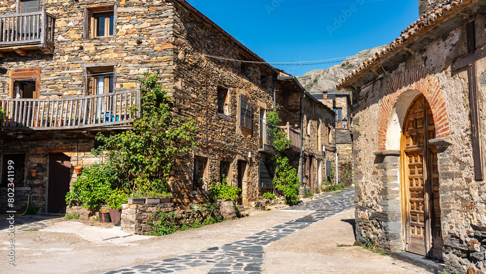 Fototapeta premium Village church with stone houses around next to the mountain, Castilla la Mancha, Spain.