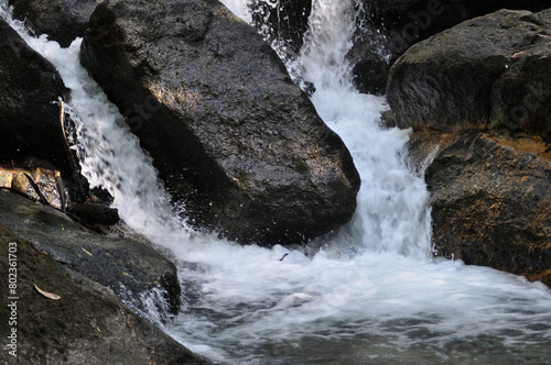 Mountain river water flowing around a rock, with motion blur