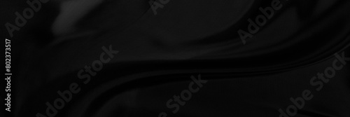 Black gray satin dark fabric texture luxurious shiny that is abstract silk cloth background with patterns soft waves blur beautiful.