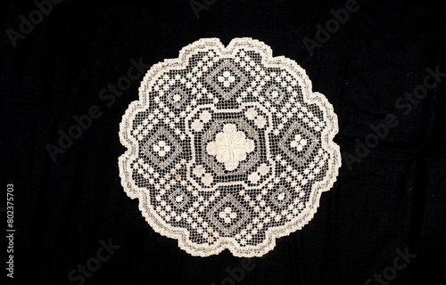 Vintage handmade white knitted napkin isolated on a black background.
